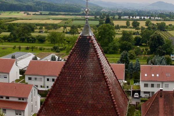 Die Spitze eines Kirchturms mit Huser im Hintergrund